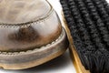 Macro photo of an old brown leather booties polished with paste, next to it lies a shoe brush, isolated on a white background. Royalty Free Stock Photo