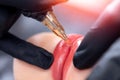 Macro photo of process of applying permanent makeup tattoo of red on lips woman