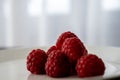 Macro photo of red raspberries on a white plate against neutral background. Simple food for a break, healthy lifestyle Royalty Free Stock Photo