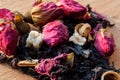 Macro photo of tea with a tea rose. The composition of the heap of tea roses and dried hibiscus flower located on a wooden Board.