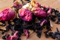 Macro photo of tea with a tea rose. The composition of the heap of tea roses and dried hibiscus flower located on a wooden Board.