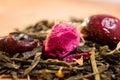 Macro photo of tea with a tea rose. The composition of the heap of tea roses and dried hibiscus flower located on a wooden Board.