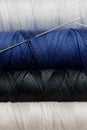 Macro photo of thread for sewing on a spool of black white and blue color with a needle