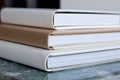 Macro photo of three closed photobooks in white and beige, lie on a glossy textured blue tabletop