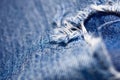 Macro photo of a torn hole in blue jeans