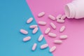 Macro Photo of white pills that pour out of a bottle on a bright blue and pink background. Medical concept Royalty Free Stock Photo