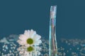 Macro photography of a transparent bottle of perfume standing on a mirror near a beautiful white flower among rhinestones Royalty Free Stock Photo