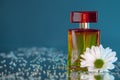 Macro photography of a yellow-red bottle of perfume standing on a mirror near a white flower among rhinestones Royalty Free Stock Photo