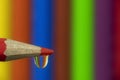 Macro of a red pencil wit a waterdrop with rainbow pattern. Royalty Free Stock Photo