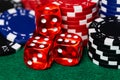 A macro of Red translucent casino style dice with white pips surrounded by reb, blue and black betting chips on a green felt Royalty Free Stock Photo