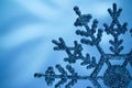 Macro shiny snowflake on blue blurred background