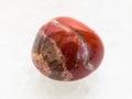 polished red Jasper gem stone on white marble Royalty Free Stock Photo
