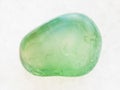 tumbled green Calcite gemstone on white marble