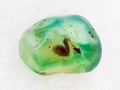 tumbled green dyed agate gemstone on white marble