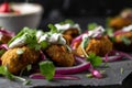 Macro shot of crispy falafel bites served with a tangy tzatziki sauce and topped with sliced red onions and fresh mint leaves