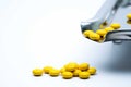 Yellow round sugar coated tablets pills on stainless steel drug tray and some of them are on white background