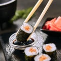 Macro shot of dipping salmon hosomaki sushi in soy sauce on natural black slate plate background with selective focus. Thin maki s Royalty Free Stock Photo