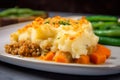 Macro shot of a dish of Shepherd pie with a crispy and golden panko breadcrumb topping, served with a side of green beans