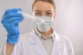 Macro shot of doctor or microbiologist in protective glasses, gloves and mask with biological tube on white laboratory background