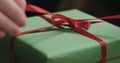 Macro shot of female hands tying red ribbon bow on green paper gift box Royalty Free Stock Photo