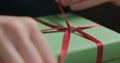 Macro shot of female hands tying red ribbon bow on green paper gift box Royalty Free Stock Photo