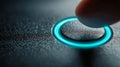 A macro shot of a finger pressing a glowing blue illuminated circular button on a textured dark surface, symbolizing technology Royalty Free Stock Photo