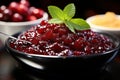 Macro shot of glistening cranberry sauce with a fresh mint garnish.