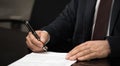 Hand of a businessman signing or writing a document on a sheet of white paper using a nibbed fountain pen. Royalty Free Stock Photo