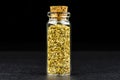 Macro shot of oregano in a small glass bottle closed with a cork, isolated on a black background. Royalty Free Stock Photo
