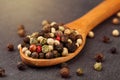 Extreme close up a of peppercorn mix in a wooden spoon on a dark stone kitchen board