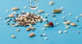 Tiny Ladybug Amongst Seeds and Water Droplets on Bright Blue Surface Royalty Free Stock Photo