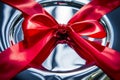 macro shot of red ribbon bow on shiny silver gift box lid Royalty Free Stock Photo