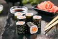 Macro shot of salmon hosomaki sushi on natural black slate plate background with selective focus. Thin maki sushi rolls with raw t Royalty Free Stock Photo