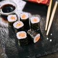 Macro shot of salmon hosomaki sushi on natural black slate plate background with selective focus. Thin maki sushi rolls with raw t Royalty Free Stock Photo