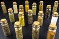 Macro shot of seventeen different spices standing in vials with a cork, isolated on a black background.