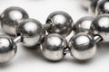 Macro shot of silver metal ball necklace on white.