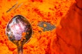 Macro shot of a spoon in a pile of orange pigment in the city of Pushkar