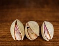 Macro Shot Three Pistachio Nuts on dark wooden Background