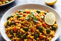 Macro shot of vegan paella showcasing the texture of saffron-infused rice, mixed with vegetables and lemon wedges on the
