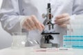 Macro shot view of microbiologist in protective gloves analyzes with microscope covid-19 vaccine on white background. Backstage of