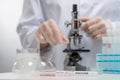 Macro shot view of microbiologist in protective gloves use microscope for study covid-19 vaccine on laboratory background.