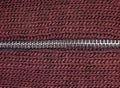 Macro shot of zipper on red wool texture background with stitching. Horizontal background from a close-up of wool material Royalty Free Stock Photo