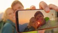 MACRO: Smiling young hiker couple taking a selfie on mountaintop at sunrise.