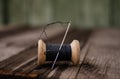 Macro of a spool of black thread and a needle with black sewing thread