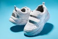 macro of two white children's floating sneakers with velcro facing each other isolated on a blue background Royalty Free Stock Photo