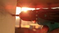 MACRO: Unrecognizable contractor uses a power drill to unscrew a bolt at sunrise