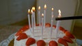 MACRO: Unrecognizable person uses a lighter to light up birthday cake candles.