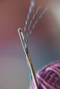 Macro view of needle, thread and ball of yarn.