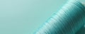 Macro view of blue thread wound on a spool against a plain teal background. Fine fibers create a subtle texture. Minimalist craft Royalty Free Stock Photo