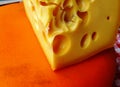 macro view of fresh Swiss cheese slice on display at street market on orange color slab Royalty Free Stock Photo